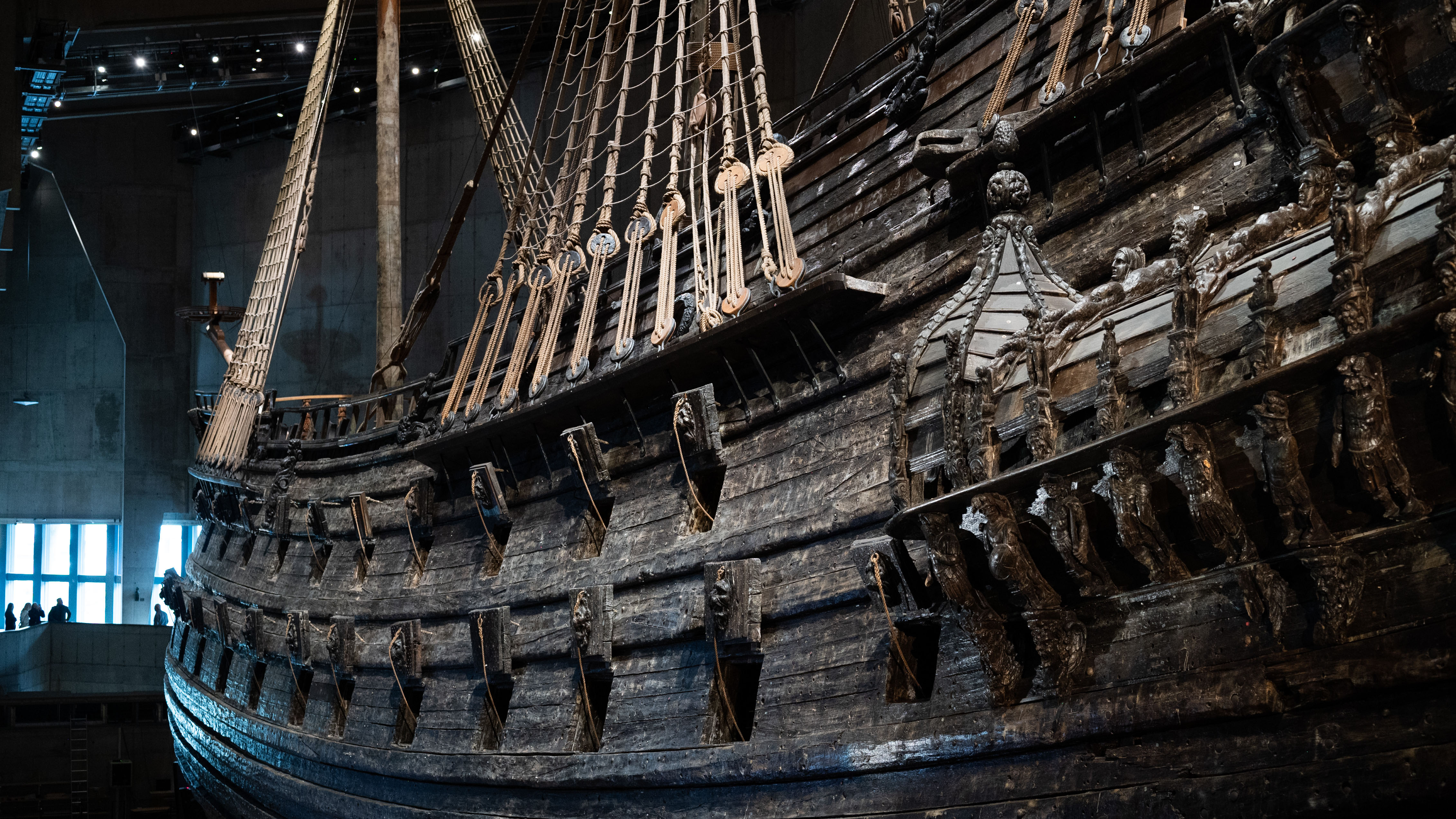 Skeppet Vasa, ett stort krigsskepp byggt i mörkt trä, sett från sidan inuti Vasamuseet. 